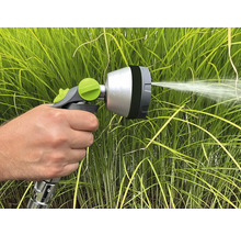 Une main tient un pistolet d'arrosage pour arroser les plantes