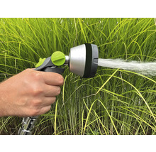 Une main tient un pulvérisateur de jardin qui projette de l'eau.