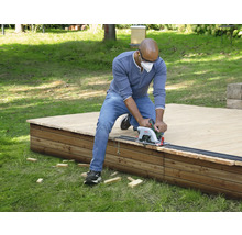 Mann sägt Holzterrasse mit Handkreissäge