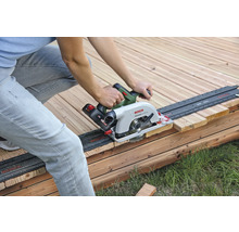 Eine Person sägt ein Holzbrett mit einer Handkreissäge auf einer Holzterrasse.