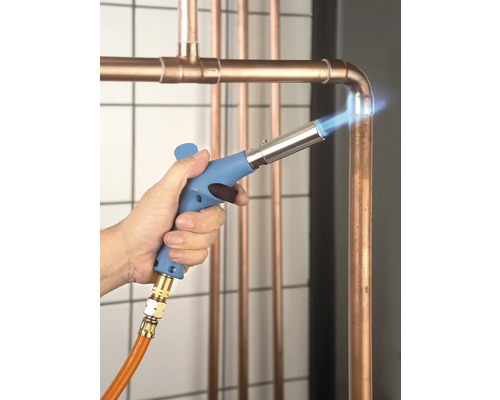 Un artisan soude des tuyaux de cuivre avec un appareil à souder.