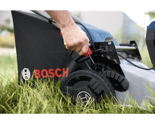 Gros plan sur une tondeuse à gazon en cours d'utilisation avec un bac de ramassage et le logo Bosch