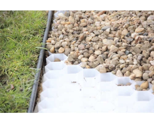 Gros plan d''une dalle de gazon remplie de gravier à côté d''une pelouse