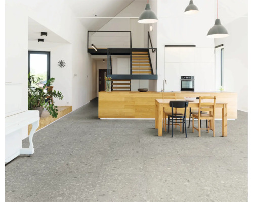 Espace de vie lumineux avec carrelage gris, table de cuisine et escalier