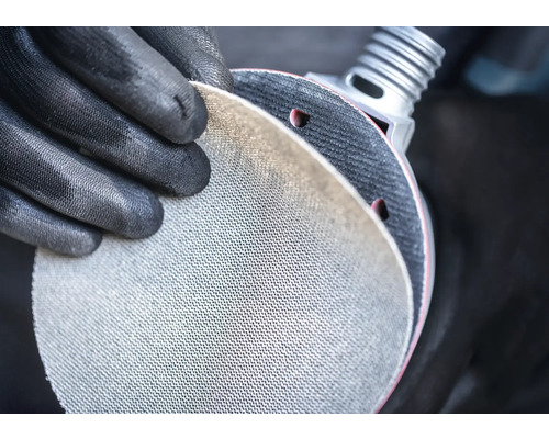 Personne avec des gants de protection tenant un disque abrasif