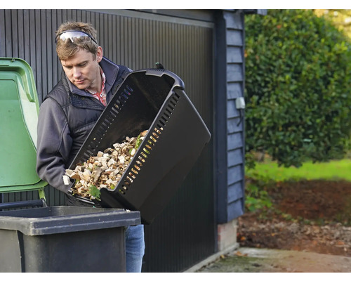 Un homme vide un récipient de déchets de jardin dans une poubelle