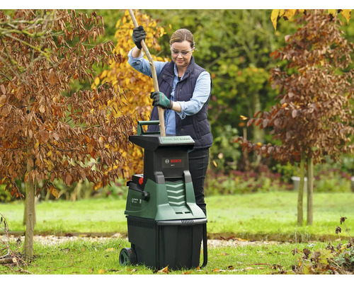 Femme utilisant un broyeur de jardin dans le jardin.