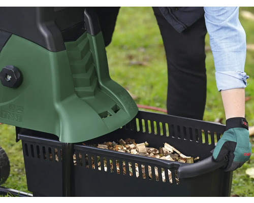 Une personne vide un broyeur de jardin dans un bac de récupération.