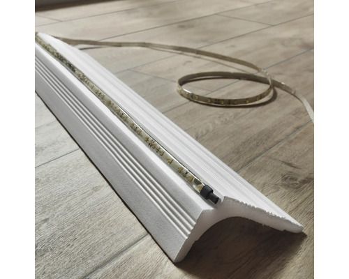 Moulure décorative blanche avec bande LED sur un sol en bois.