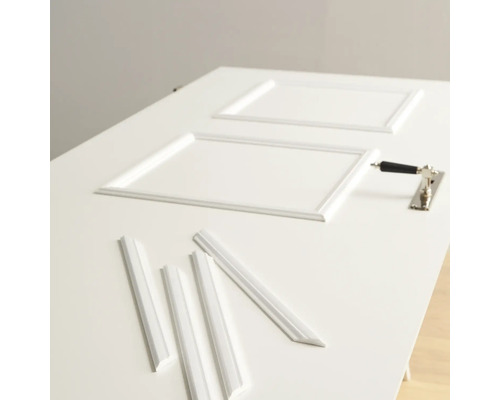 Auf einer Tür liegen Zierleisten und ein Türgriff.