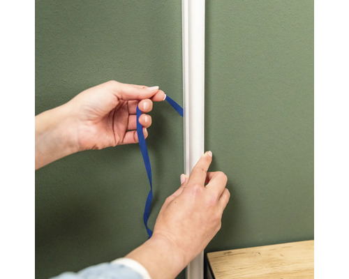 Les mains mesurent avec un ruban la distance par rapport à la moulure décorative