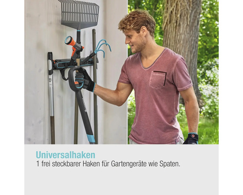 Mann hängt Gartengeräte an eine Gerätehalterung