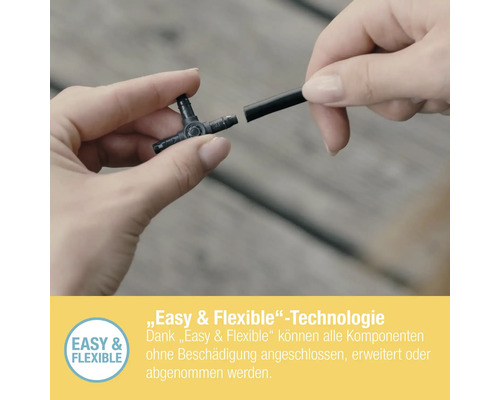 Une personne connecte un té à un tuyau d''arrosage.