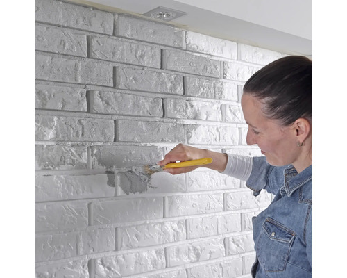 Femme peignant un mur de briques avec un pinceau