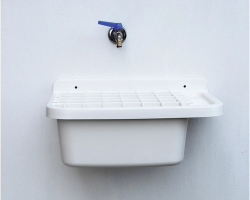 Weisses Ausgussbecken mit Armatur an einer Wand montiert