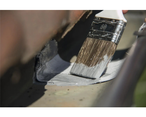 Anstreichen einer Dachrinne mit einem Pinsel.