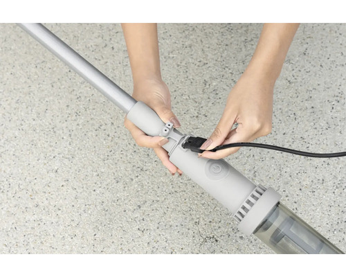 Une personne branche le câble d''un aspirateur de piscine