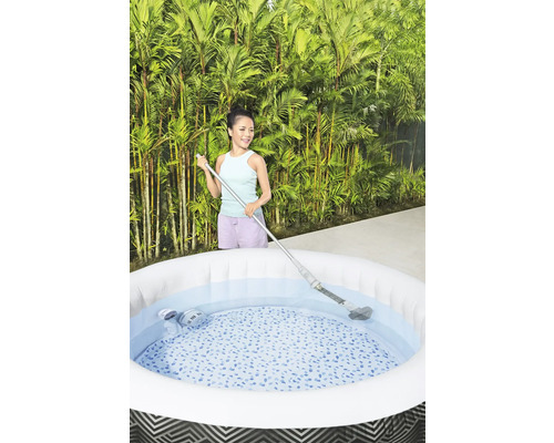 Femme nettoie un jacuzzi gonflable avec un aspirateur