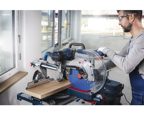 Gehrungssäge beim Schneiden eines Holzstücks, bedient von einem Handwerker