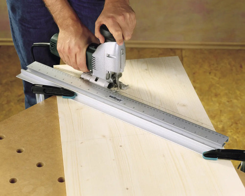 Artisan utilisant une scie sauteuse avec un rail de guidage sur du bois