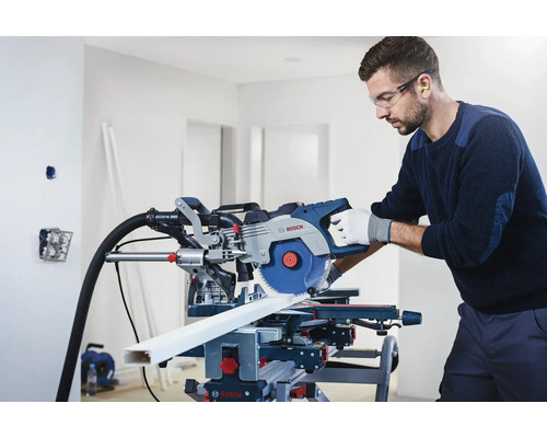 Homme portant des lunettes de sécurité et une protection auditive utilisant une scie à onglets Bosch pour couper une pièce