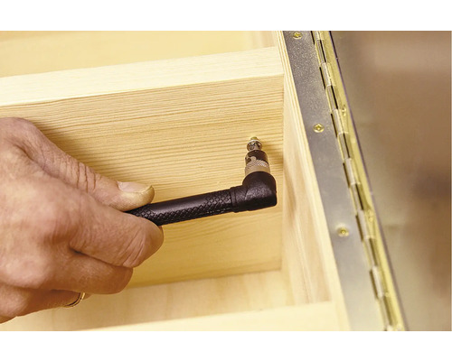 Hand schraubt Schraube in Holz mit Winkelaufsatz