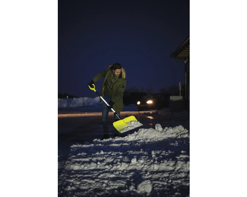 Mann schaufelt Schnee mit einer Schneeschaufel vor einem Haus