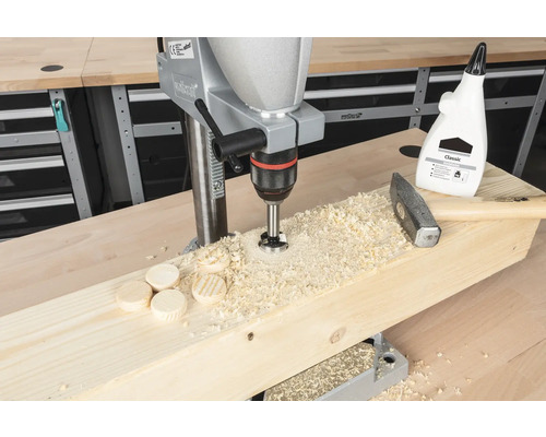 Perceuse à colonne perçant des chevilles en bois dans une planche de bois, avec un marteau et de la colle à bois