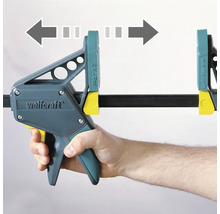 Serre-joint à une main Wolfcraft en utilisation avec des flèches indiquant la direction de serrage