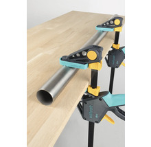 Les serre-joints Wolfcraft maintiennent un tube sur un plateau de table.
