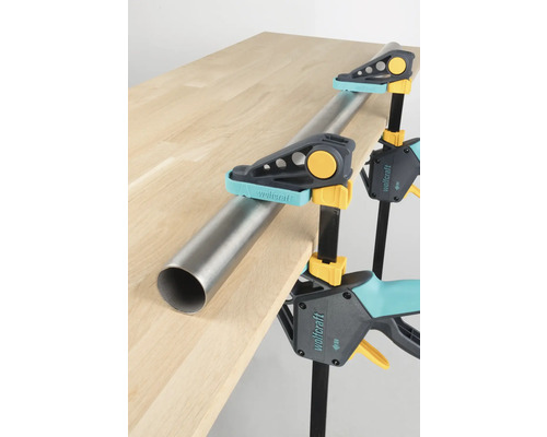 Pièce maintenue par des serre-joints à une main Wolfcraft et un tube sur un plateau de table.