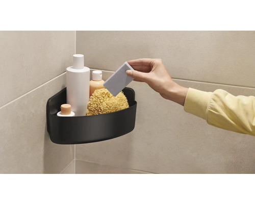 Coin avec étagère de douche noire, remplie de produits de bain et d''une éponge de bain