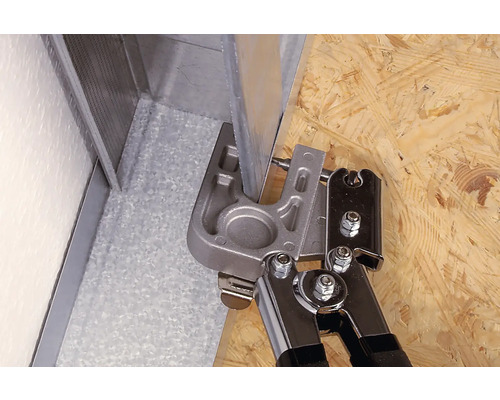 Pince à border travaillant un profilé métallique sur une surface en bois.