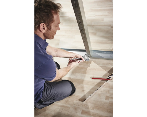 Un homme fixe un profilé métallique avec une pince dans une construction sèche