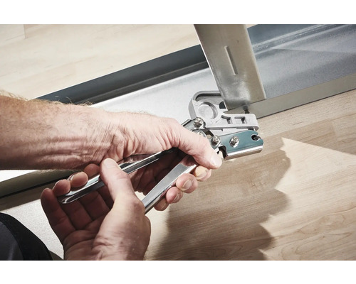 Des mains utilisent une pince à poinçonner sur un profilé métallique