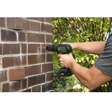 Mann bohrt Loch in Ziegelwand mit Akku-Bohrschrauber