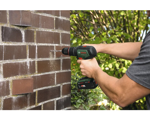 Mann bohrt Loch in Ziegelwand mit Akku-Bohrschrauber