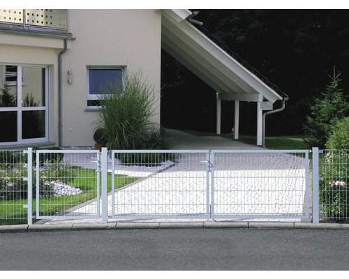 Clôture métallique devant une maison d''habitation avec une allée pavée