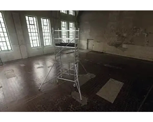 Échafaudage dans une pièce vide avec de grandes fenêtres pour les travaux de construction.