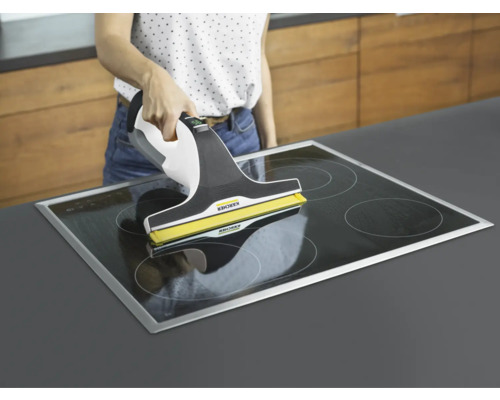 Femme nettoyant une plaque de cuisson vitrocéramique avec un aspirateur de vitres