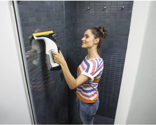 Femme nettoie une cabine de douche avec un aspirateur de fenêtre
