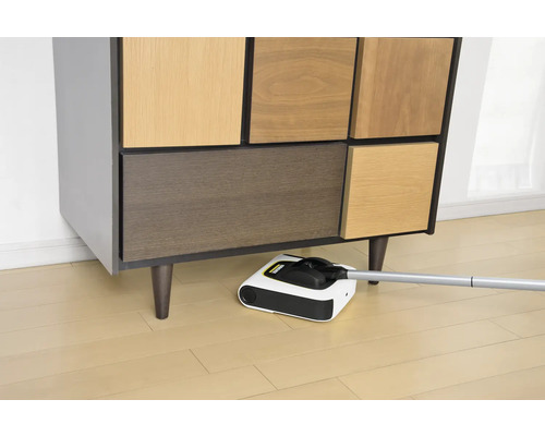 Un nettoyeur de sols sans fil est utilisé sous une armoire.