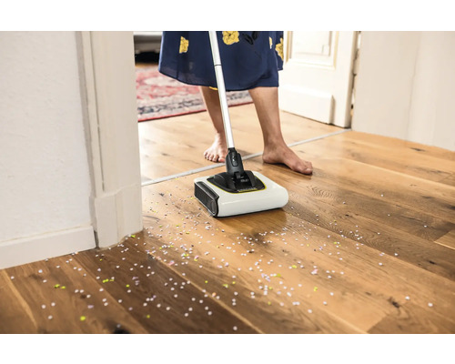 Balai sans fil en cours d''utilisation sur un sol en bois avec des confettis