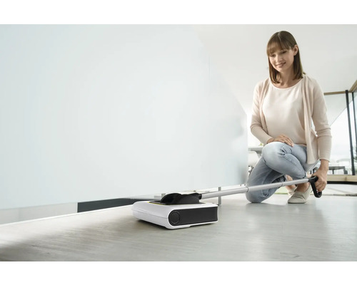 Femme utilise une balayeuse électrique pour nettoyer le sol