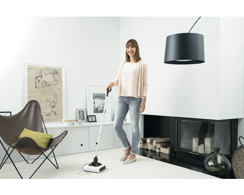 Une femme utilise un balai à piles pour nettoyer un salon.