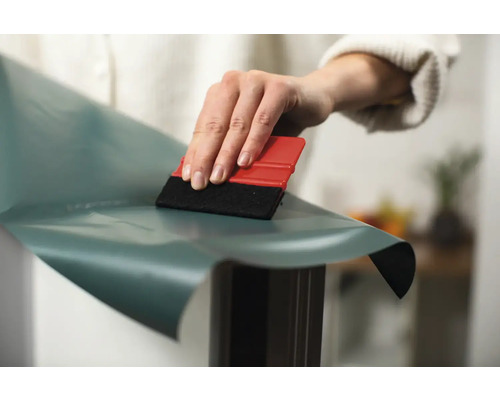 Personne appliquant un film décoratif avec une raclette