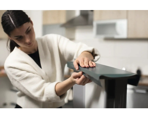 Femme assemblant un meuble dans la cuisine.