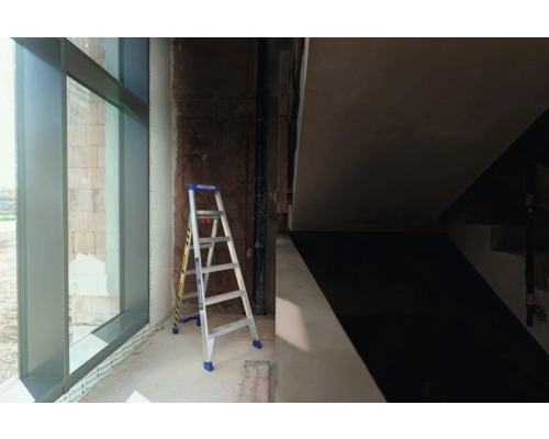 Une échelle est placée dans un bâtiment en construction à côté d''une fenêtre.