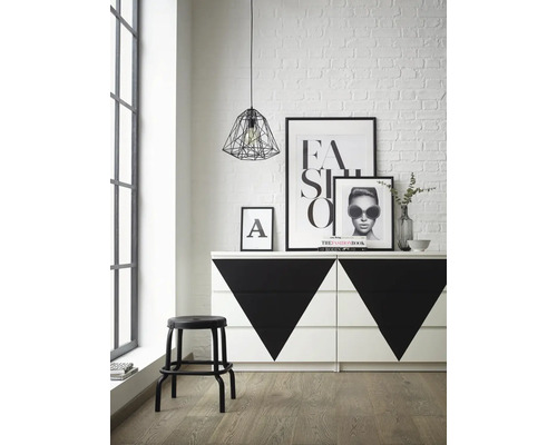 Photo d''intérieur d''une pièce avec une commode à motifs géométriques, un tabouret, des affiches et une suspension.