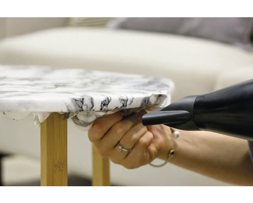 Application d''un film pour meubles à l''aide d''un pistolet thermique sur une table